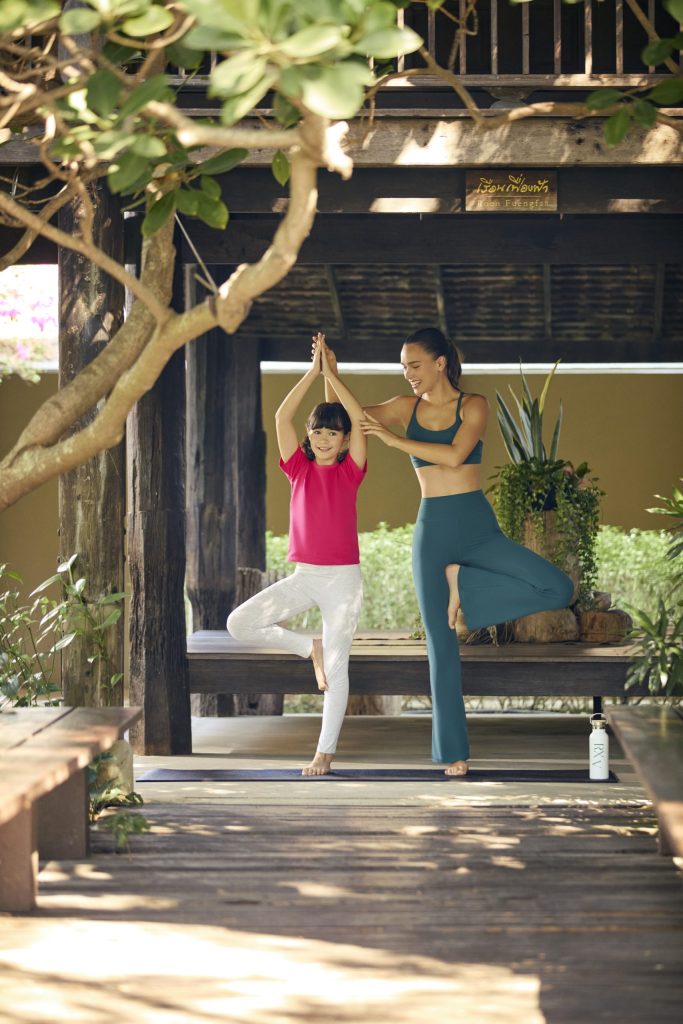 Mother and daughter practicing yoga together at RXV Wellness Village, connecting mind and body in a serene garden space.