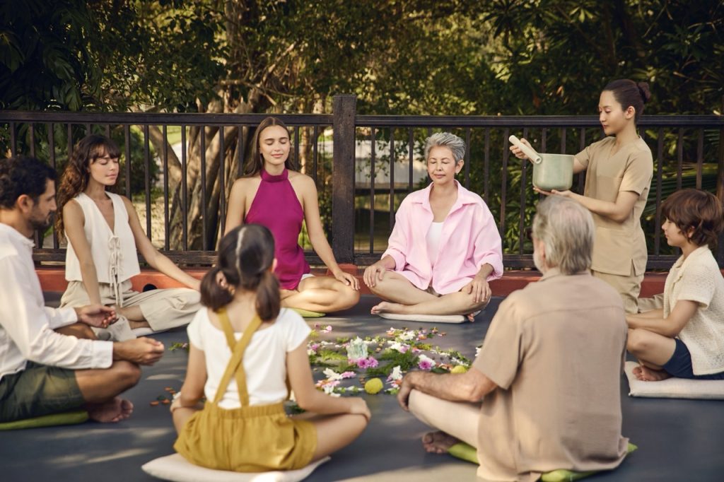 Group meditation and sound healing session at RXV Wellness Village, bringing together families across generations for mindfulness and relaxation.
❓ How does sound healing at RXV Wellness Village nurture harmony and wellbeing for all ages?