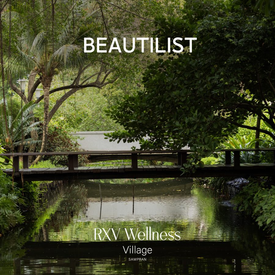 Scenic view of RXV Wellness Village Sampran featured in Beautilist — a tranquil bridge surrounded by lush greenery and water reflection