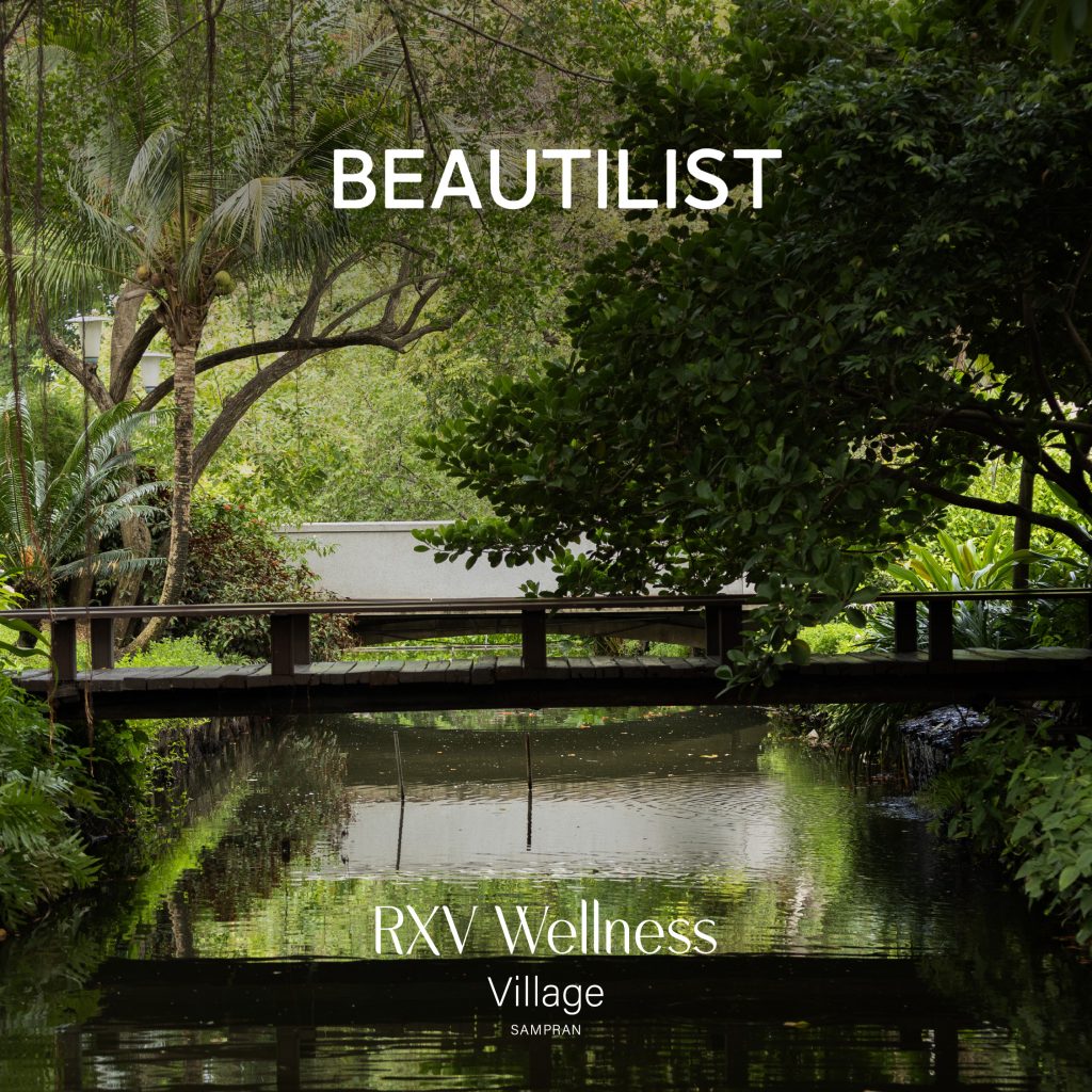 Scenic view of RXV Wellness Village Sampran featured in Beautilist β a tranquil bridge surrounded by lush greenery and water reflection