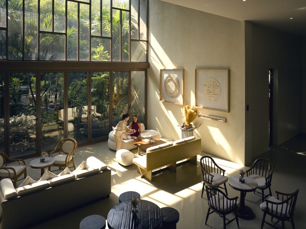 Tranquil lounge area at RXV Wellness Village filled with natural light, offering a serene space for guests to unwind and connect.