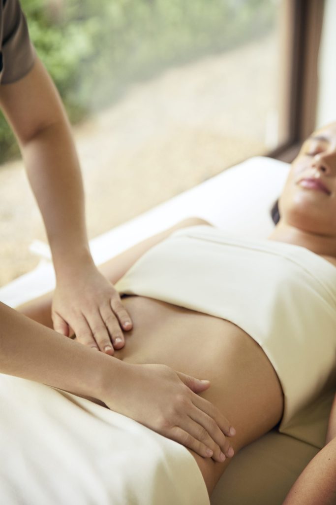 Therapist performing abdominal massage for gut health at RXV Wellness Village.