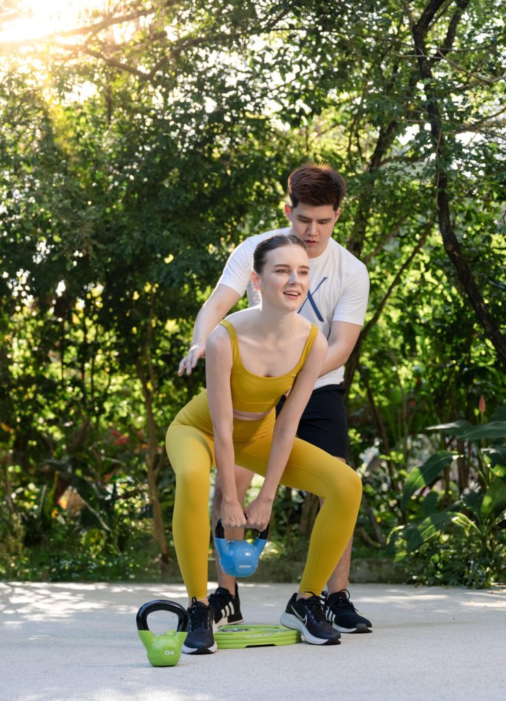 Personal training session at RXV Wellness Village, with a coach guiding a guest through a kettlebell workout surrounded by nature.