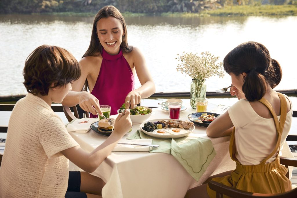 Family enjoying a nutritious wellness meal by the river at RXV Wellness Village.
