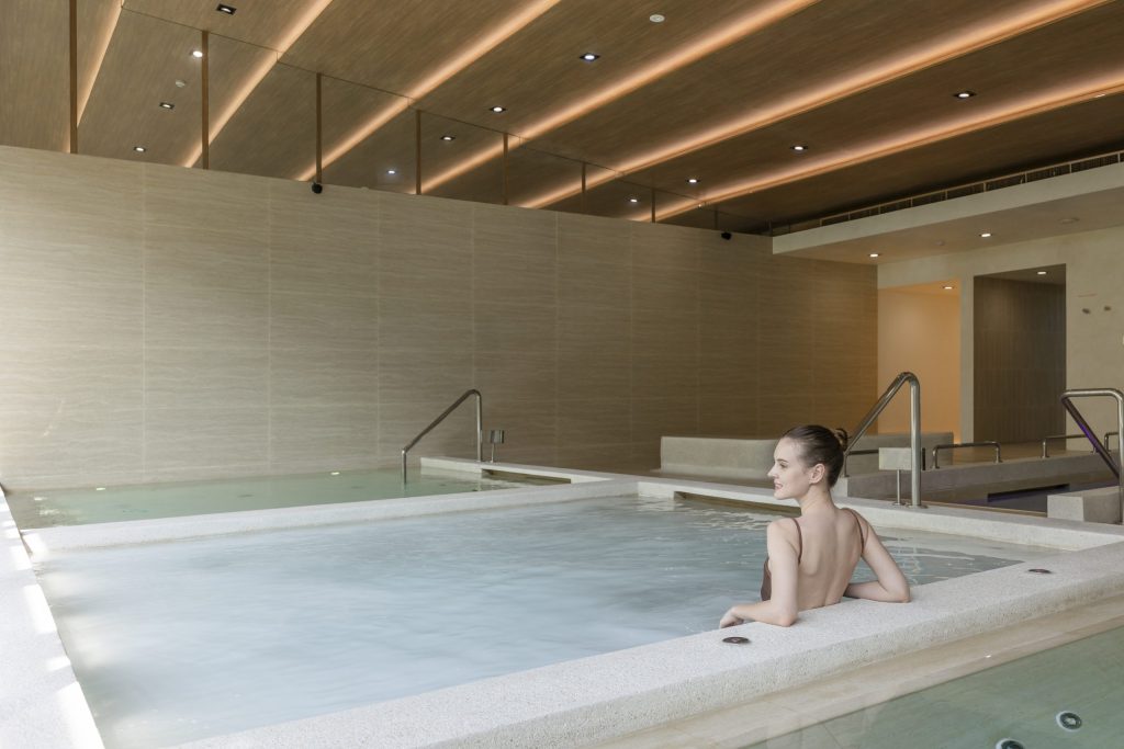 Woman relaxing in hydrotherapy pool at RXV Wellness Village, featured in Age Traveller Spa Horizons