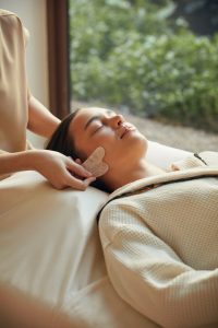 Close-up of a woman receiving a gentle facial massage surrounded by nature at RXV Wellness Village Sampran.