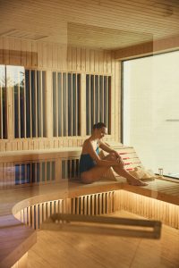 Woman relaxing in a wooden infrared sauna room at RXV Wellness Village Sampran.