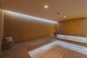 Interior of the steam room at RXV Wellness Village Sampran, featuring warm lighting, natural stone textures, and a serene minimalist design.
