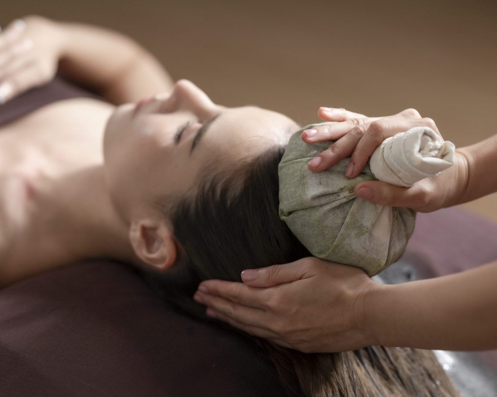 Woman receiving herbal compress therapy at RXV Wellness Village Sampran, featured in Falstaff Travel