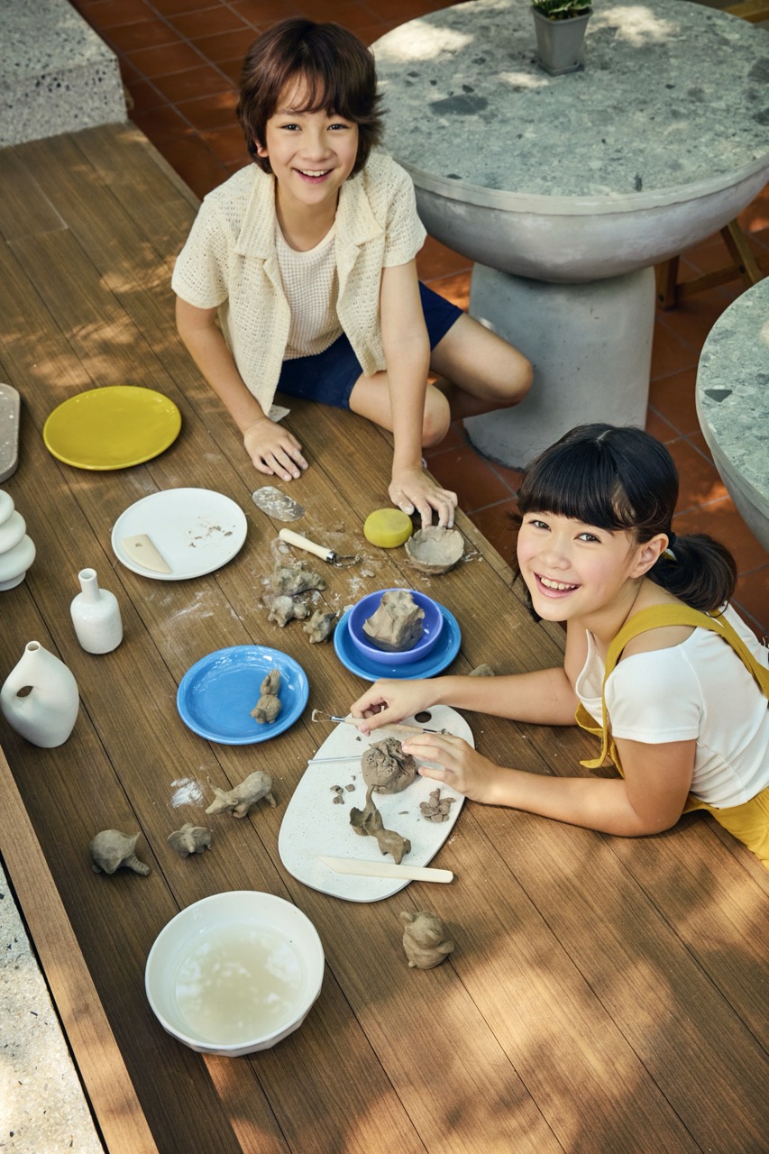 Children sculpting clay in an outdoor pottery workshop at RXV Wellness Village Sampran.