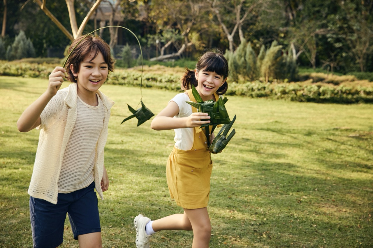 Children playing outdoors with traditional palm leaf crafts at RXV Wellness Village Sampran.