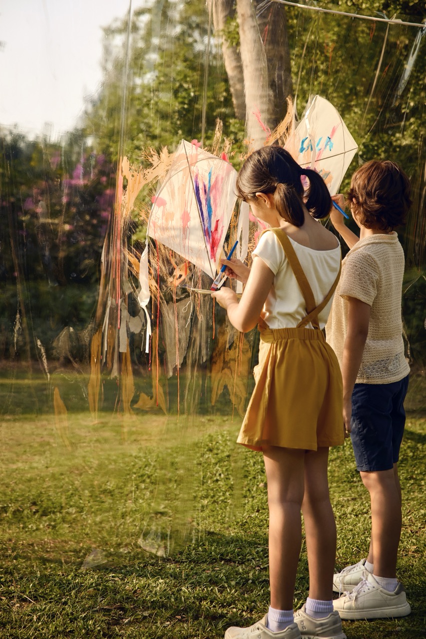 Children painting on transparent canvas outdoors at RXV Wellness Village Sampran.